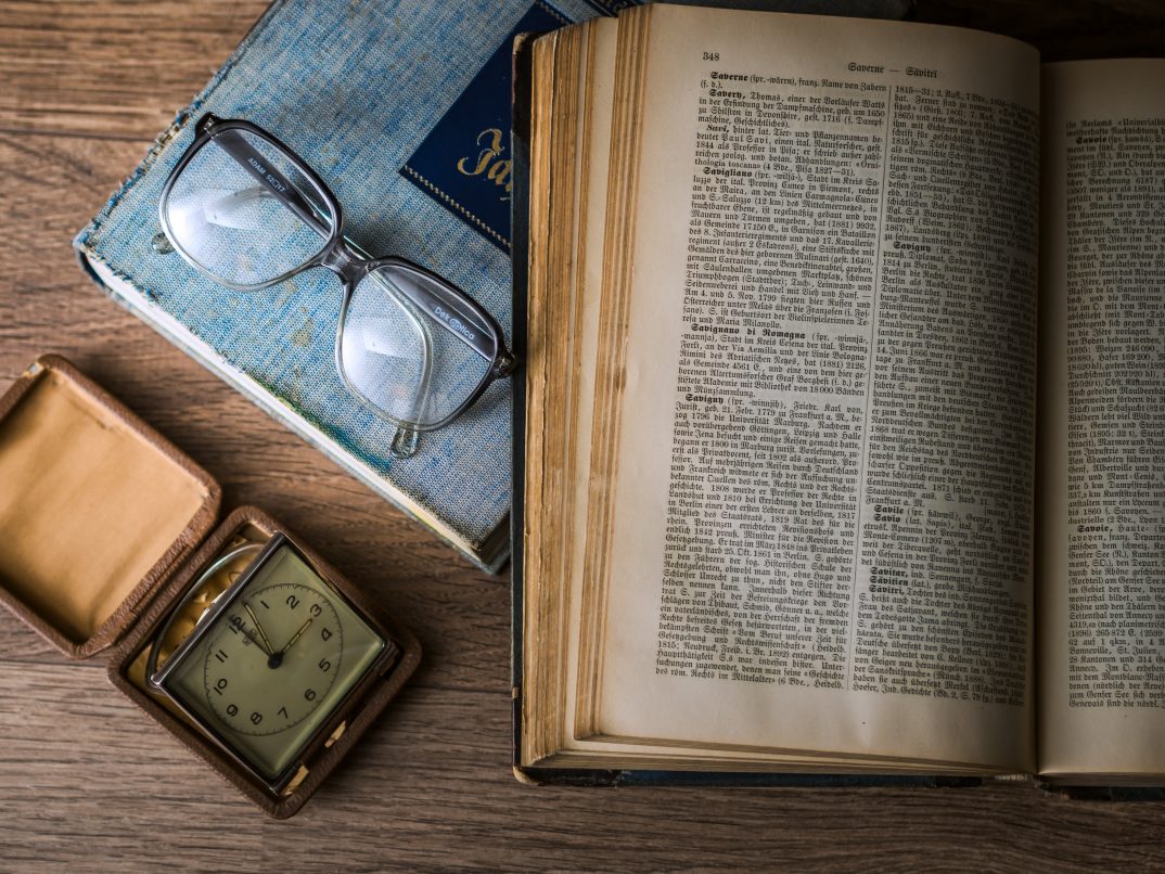 De gauche à droite, un cadran ancien, une paire de lunettes de vue et des livres anciens